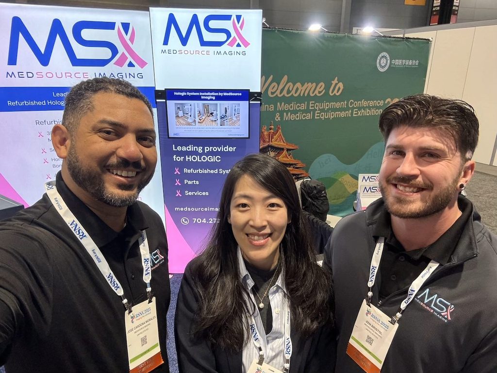 MedSource Imaging team smiling in a selfie at the MedSource Imaging booth at RSNA 2025, in front of banners advertising refurbished Hologic systems, parts, and services.